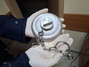 Policjant trzyma metalową nasadę od hydrantu.