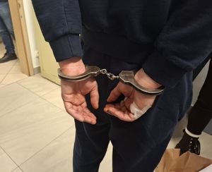 Policjanci wykonują czynności z zatrzymanym mężczyzną.