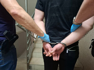 Policjanci prowadzą osobe zatrzymaną.