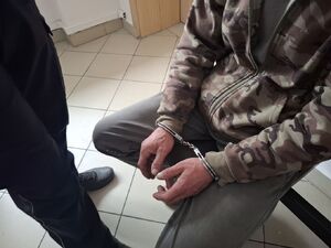 Osoba ma założone kajdanki na ręce.