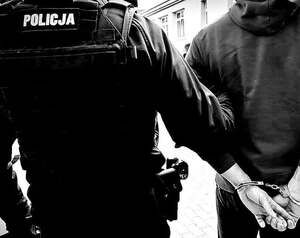 Policjant prowadzi osobę zatrzymaną.