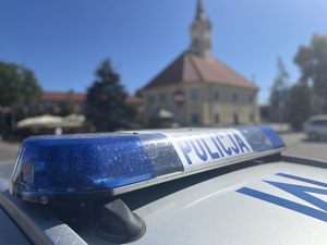 Radiowóz stoi na tle ratusza miejskiego.