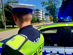 Policjant stoi przy radiowozie.