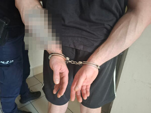 Policjant prowadzi zatrzymanego.
