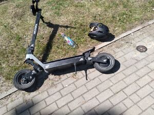 Hulajnoga i kask ochronny leżą na ulicy.