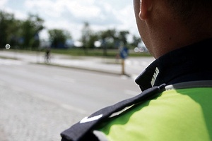 Policjant stoi obok przejścia dla pieszych.