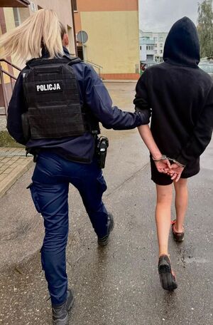 Policjantka prowadzi osobę zatrzymaną