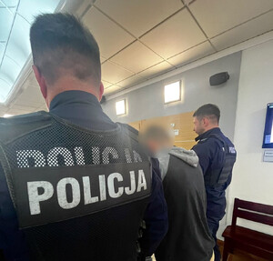 Policjanci doprowadzają zatrzymanego mężczyznę.
